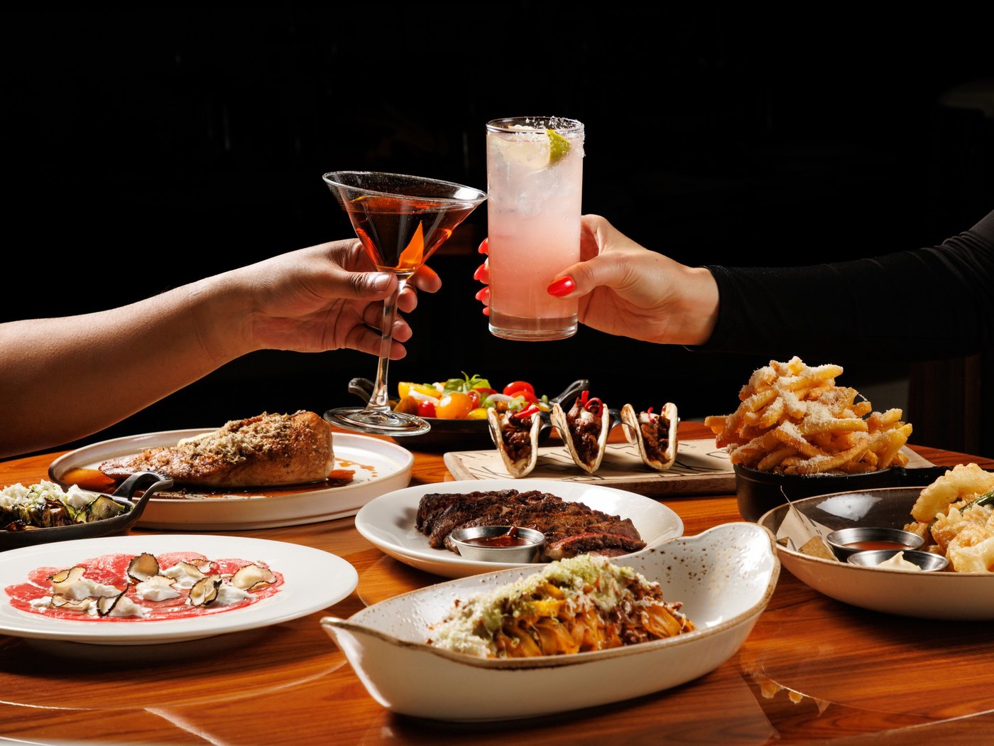 Cozy Method steakhouse guide: cocktails raised over a full table of steakhouse dishes at STK Steakhouse in Salt Lake City